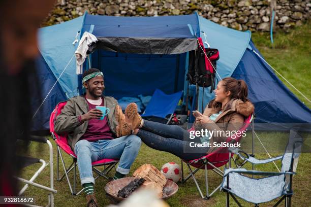 friends relaxing outside tents on camping holiday - music festival field stock pictures, royalty-free photos & images