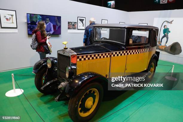 Person walks past comics strip character Gaston Lagaffe's car exhibited on the first day of the Paris Book Fair 2018 at the Parc des Expositions in...