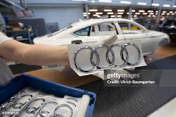 Car production at Audi AG in Ingolstadt. The hand of a worker with the Audi logo in front of the car production line.