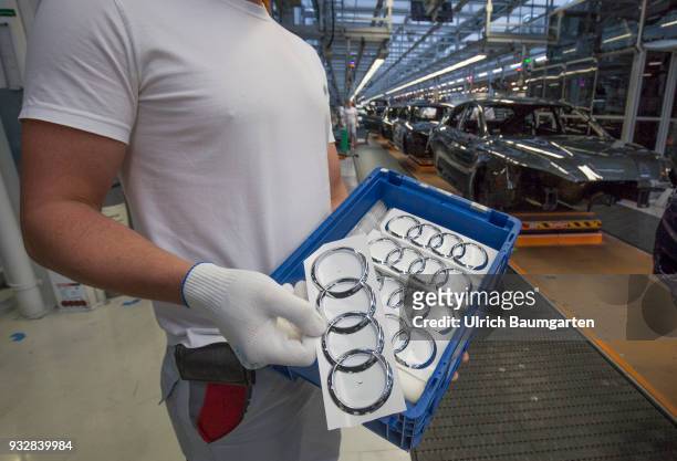 Car production at Audi AG in Ingolstadt. The hand of a worker with the Audi logo in front of the car production line.
