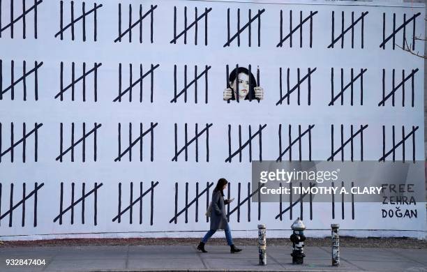 Woman passes by a new 70-foot-long mural by anonymous British artist Banksy on March 16, 2018 that was unveiled on March 15, 2018 at the corner of...