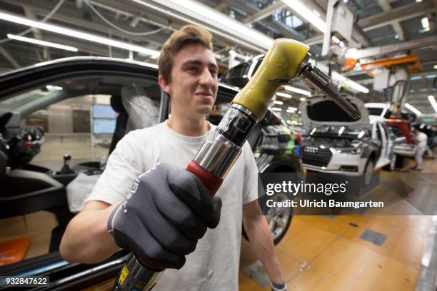 Car production at Audi AG in Ingolstadt. Installation of the front seats on the Audi A3/Q2 - worker with mounting key.