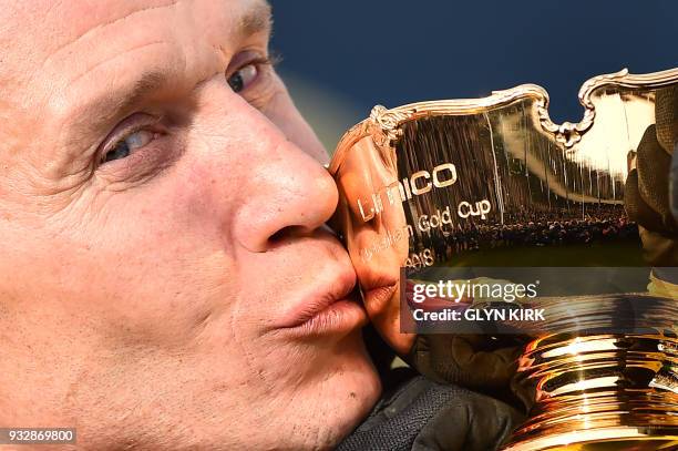 Jockey Richard Johnson kisses the trophy as he celebrates after winning the Gold Cup race riding Native River on the final day of the Cheltenham...