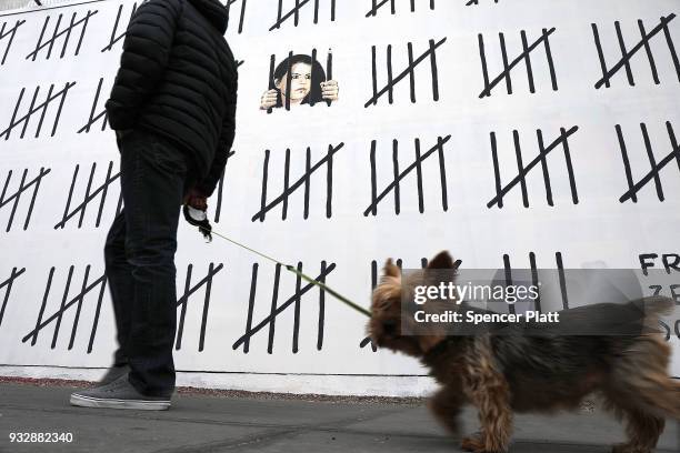 Pedestrians walk by the latest work by the elusive British street artist Bansky along a wall on Houston street in Manhattan on March 16, 2018 in New...