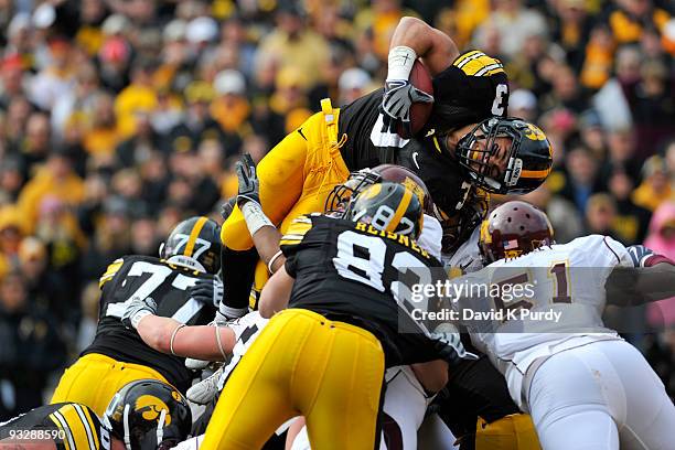 Running back Brandon Wegher of the Iowa Hawkeyes jumps into the end zone for a one yard touchdown as linebacker Gary Tinsley of the Minnesota Golden...