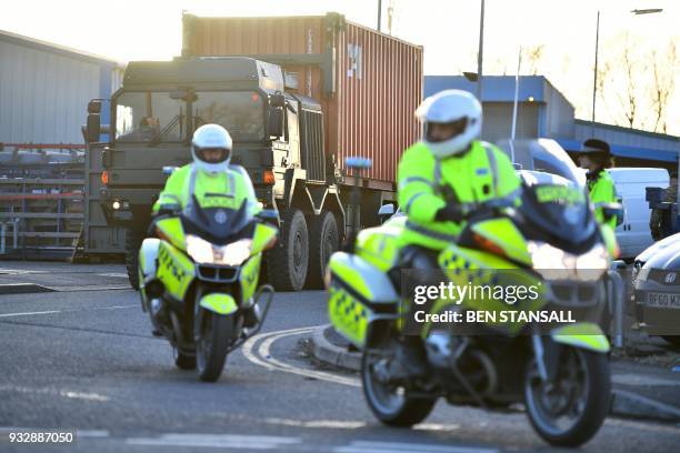 Police officers escort an army truck, carrying a freight container laden with the car of Sergei Skripal, as it is driven from the Churchfields...