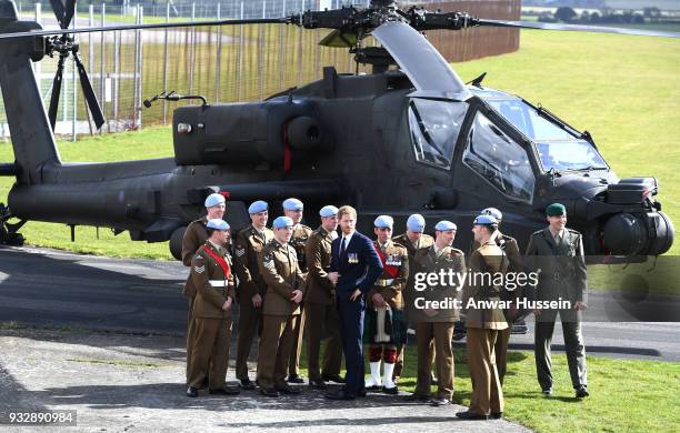 Prince Harry poses in front of an Apache helicopter with Army Air Corps pilots after presenting Wings during a ceremony at Museum of Army Flying in...