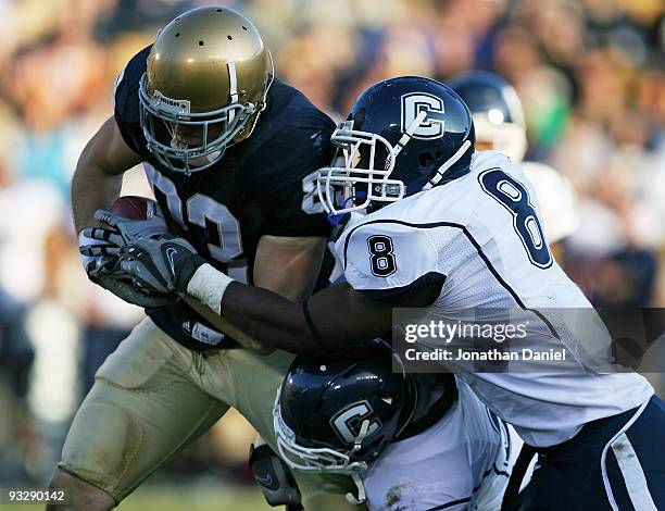 Robby Parris of the Notre Dame Fighting Irish is brought down by Robert Vaughn and Lawrence Wilson of the Univeristy of Connecticut Huskies at Notre...