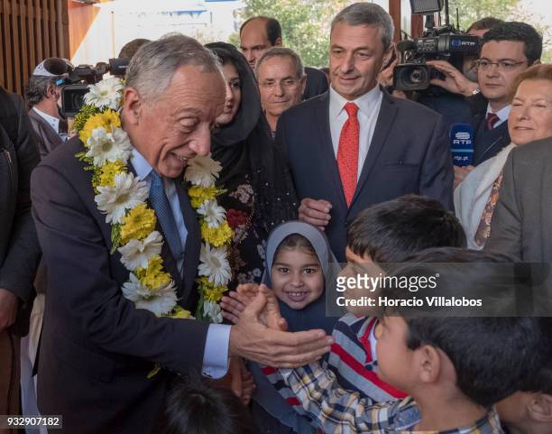 Portuguese President Marcelo Rebelo de Sousa wears a garland of flowers while being greeted by community children in the city's Central Mosque upon...
