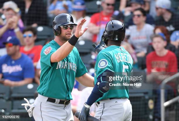 Kirk Nieuwenhuis of the Seattle Mariners is congratulated by teammate Guillermo Heredia after scoring on a hit by Jean Segura against the Texas...