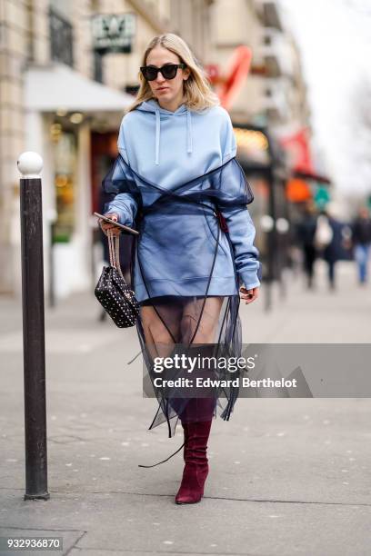 Guest wears sunglasses, a baby blue hoodie, a baby blue mini skirt, a fringe black chiffon dress, plum suede over-knee boots, a black studded...