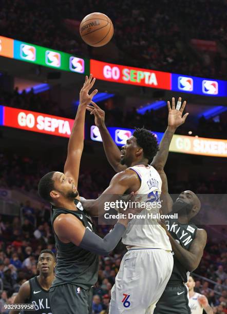 Joel Embiid of the Philadelphia 76ers gets off a shot between Jahlil Okafor and Quincy Acy of the Brooklyn Nets at the Wells Fargo Center on March...