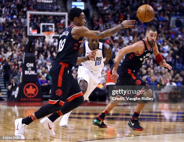 DeMar DeRozan of the Toronto Raptors passes the ball as Jonas Valanciunas and Dorian Finney-Smith of the Dallas Mavericks defends during the second...