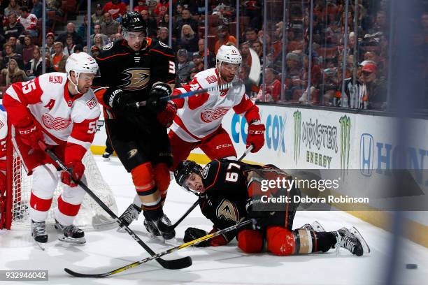 Derek Grant and Rickard Rakell of the Anaheim Ducks battle for the puck against Niklas Kronwall and Luke Glendening of the Detroit Red Wings during...