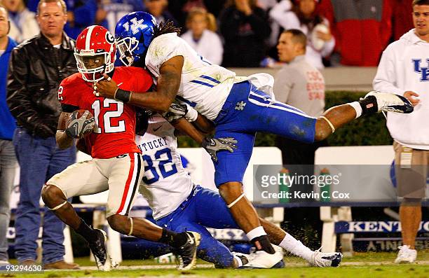 Tavarres King of the Georgia Bulldogs is tackled by Trevard Lindley and Winston Guy Jr. #21 of the Kentucky Wildcats at Sanford Stadium on November...