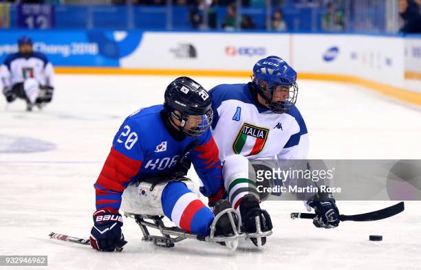 Dong Shin Jang of Korea battles for the puck with Florian Planker of Italy in the Ice Hockey bronze medal game between Korea and Italy during day...