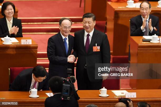 Wang Qishan , former secretary of the Central Commission for Discipline Inspection, shakes hands with China's President Xi Jinping as he is elected...