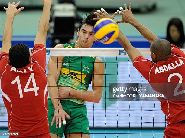 Gilberto Godoy Filho of Brazil spikes the ball through the arms of Ahmed Elshikh and Abdalla Ahmed of Egypt during their match at the men's Grand...