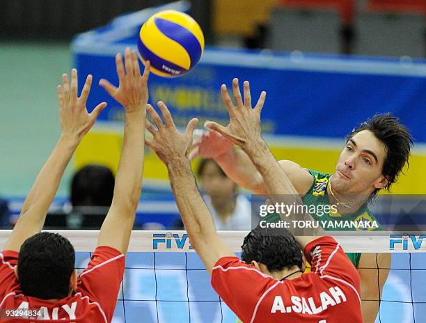 Gilberto Godoy Filho of Brazil spikes the ball through the arms of Ahmed Elshikh and Ahmed Abdelhay of Egypt during their match at the men's Grand...