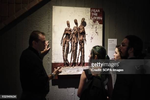 People are watching the exhibition. 54 artists are inspired by "The Walking Dead" and they present their own perspective in the post-apocalyptic and...