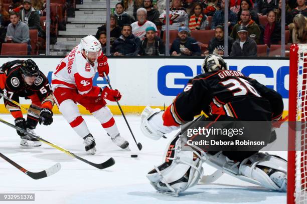 Luke Glendening of the Detroit Red Wings controls the puck against Rickard Rakell and John Gibson of the Anaheim Ducks during the game on March 16,...