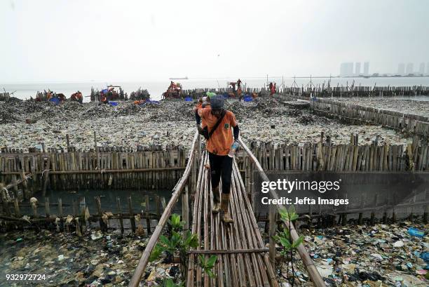 Workers collect trash during a clean up of the waters of Jakarta Bay on March 2018 in Jakarta, Indonesia. Jakarta's waters are polluted, contributing...