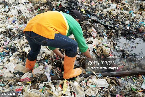 Workers collect trash during a clean up of the waters of Jakarta Bay on March 2018 in Jakarta, Indonesia. Jakarta's waters are polluted, contributing...