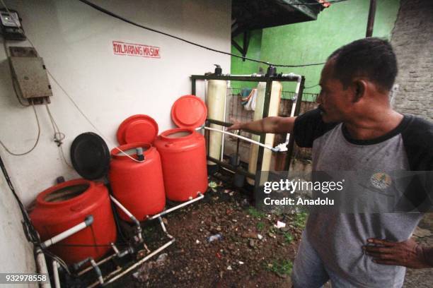 Resident shows the filtering process of river water to meet the needs of their religion demands in Sukamaju Village, Majalaya, West Java, Indonesia,...