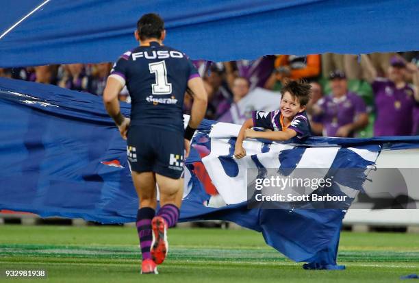 Billy Slater of the Melbourne Storm goes to help his son Jake as he gets stuck in the banner that celebrates Slaters 300th game during the round two...