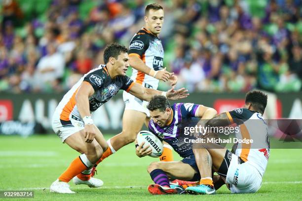 Billy Slater of the Storm is tackled by Kevin Naiqama during the round two NRL match between the Melbourne Storm and the Wests Tigers at AAMI Park on...