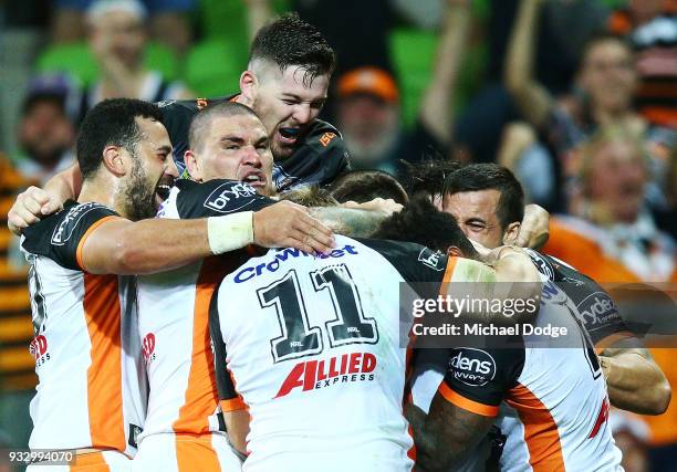 Luke Brooks of the Tigers celebrates a try in the dying stages with teammates during the round two NRL match between the Melbourne Storm and the...