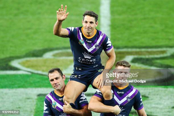 Billy Slater is carried off by Cameron Smith and Ryan Hoffman of the Storm after playing his 300th match during the round two NRL match between the...