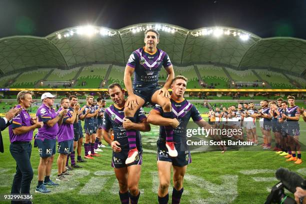 Billy Slater of the Melbourne Storm is chaired off by teammates Cameron Smith of the Melbourne Storm and Ryan Hoffman of the Melbourne Storm after...