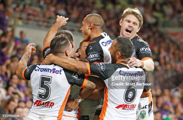Luke Brooks of the Tigers is congratulated by his teammates after scoring the winning try during the round two NRL match between the Melbourne Storm...
