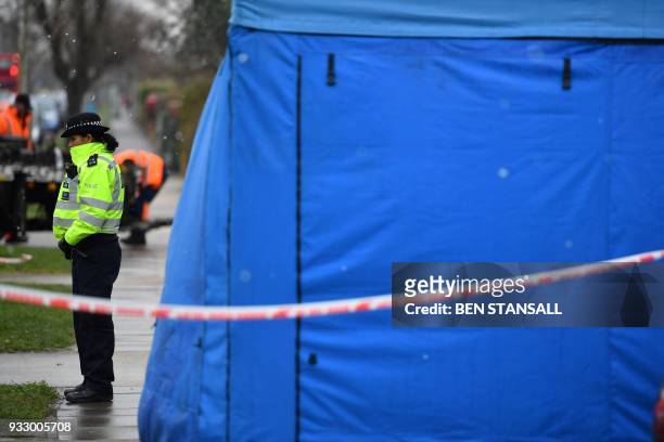 Police officer stands at the cordon by a forensics tent in front of the home of slain Russian exile Nikolai Glushkov in southwest London on March 17,...
