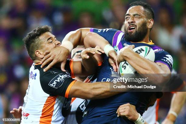 Esan Marsters of the Tigers tackles Sam Kasiano of the Storm during the round two NRL match between the Melbourne Storm and the Wests Tigers at AAMI...