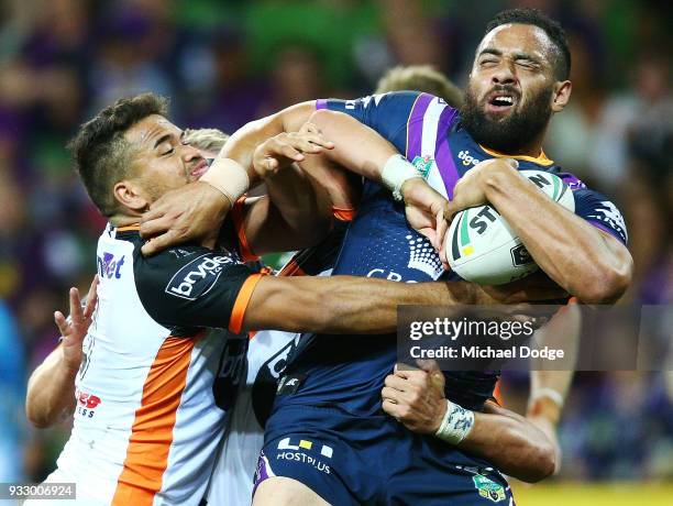 Esan Marsters of the Tigers tackles Sam Kasiano of the Storm during the round two NRL match between the Melbourne Storm and the Wests Tigers at AAMI...