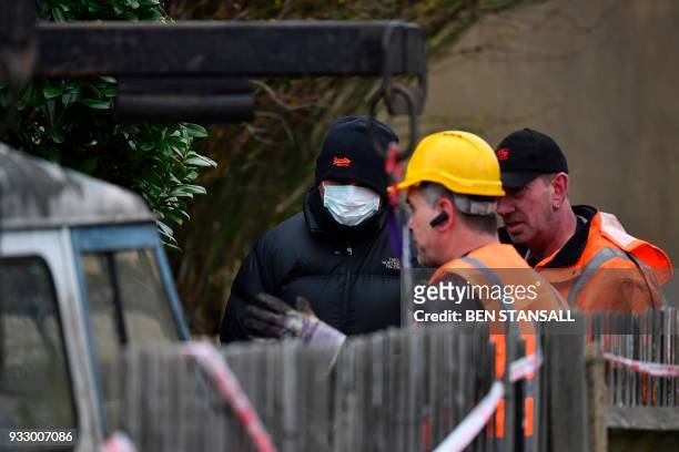Police officer talks to vehicle recovery workers as they work to remove a vehicle from a driveway leading to the rear of the home where Russian exile...