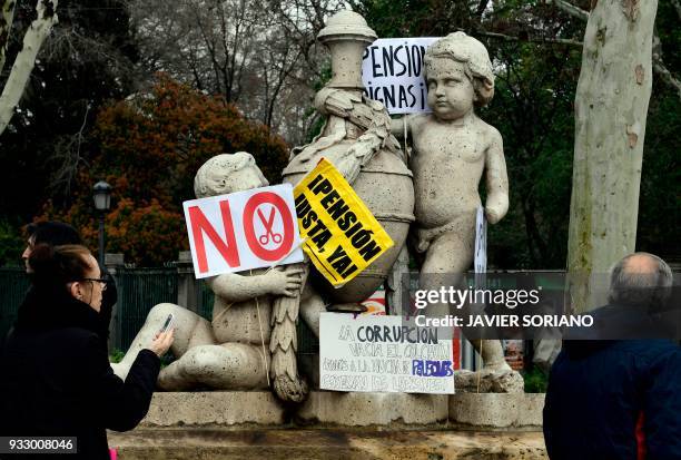 Statue is covered with placards used by demonstrators in Madrid on March 17 during a protest called by the main Spanish unions and the 'State...