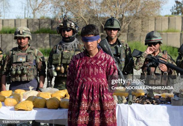 Afghan security personnel present a Taliban fighter dressed as a woman to the media at the Afghan National Army headquarters in Jalalabad on March...