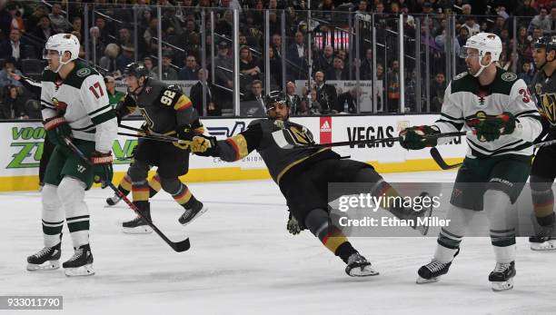 Pierre-Edouard Bellemare of the Vegas Golden Knights falls to the ice between defenders Marcus Foligno and Nate Prosser of the Minnesota Wild in the...