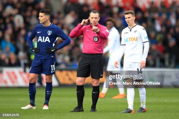 Referee Kevin Friend consults VAR as the players look on during the Emirates FA Cup Quarter Final match between Swansea City and Tottenham Hotspur at...