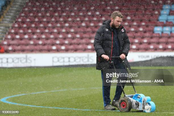 Scunthorpe United's ground staff paint the lines blue as snow falls during the Sky Bet League One match between Scunthorpe United and Shrewsbury Town...