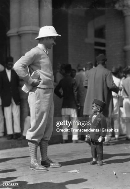 Western tourist converses with a midget in Bombay during a visit there around 1930.