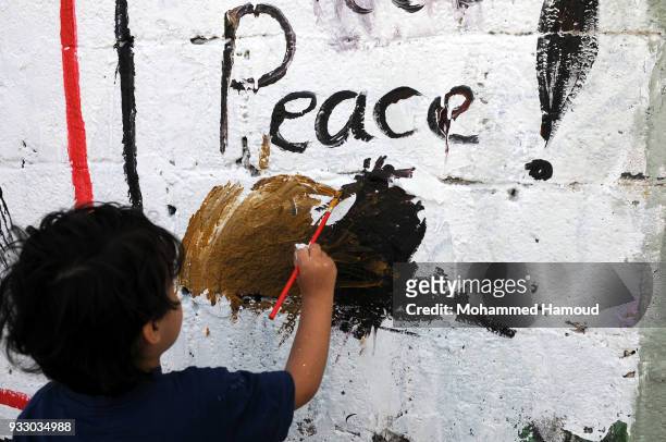 Yemeni child draws as he takes part in an Open Day of graffiti campaign call for peace on March 15, 2018 in Sana'a, Yemen.