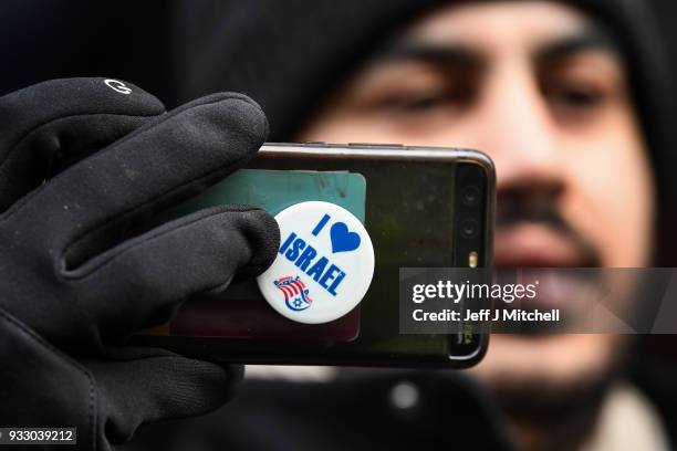 Man holds a phone with a Pro-Israeli sticker on it during an anti-racism rally through the city centre on March 17, 2018 in Glasgow, Scotland. The...