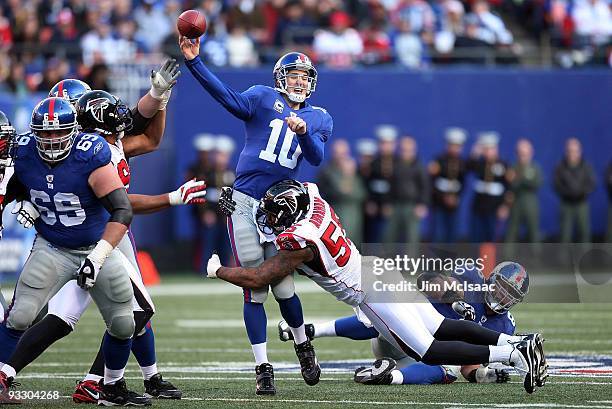 Eli Manning of the New York Giants completes a pass under pressure from John Abraham of the Atlanta Falcons on November 22, 2009 at Giants Stadium in...