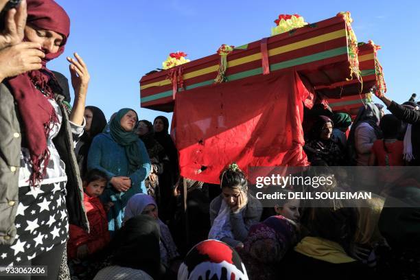 Syrian Kurdish women mourn by the coffins of People's Protection Units fighters during their funeral in the northeastern city of Qamishli on March 17...