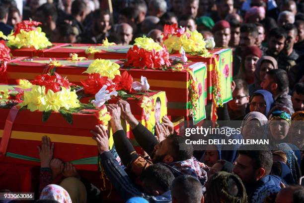 Syrian Kurds bid their farewell as they mourn by the coffins of People's Protection Units fighters during their funeral in the northeastern city of...