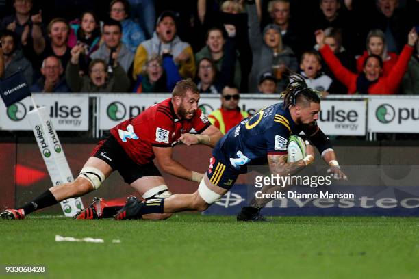 Elliot Dixon of the Highlanders dives over to score a try in the tackle of Luke Romano of the Crusaders during the round five Super Rugby match...